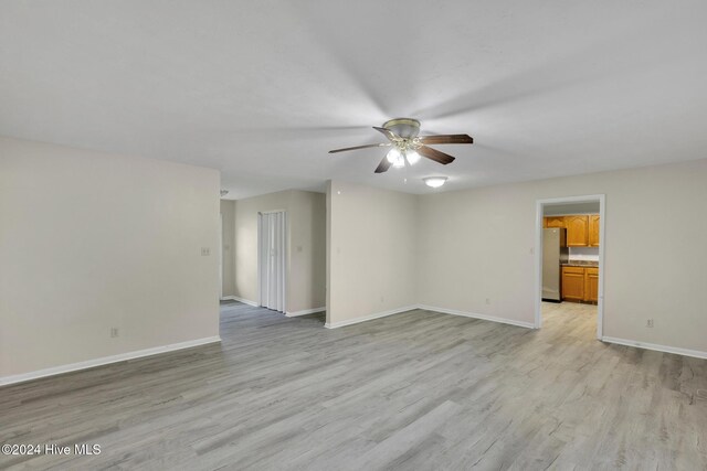 empty room with ceiling fan and light hardwood / wood-style floors