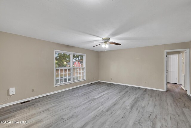 empty room with ceiling fan and light hardwood / wood-style floors