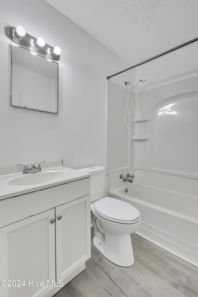 full bathroom featuring shower / bath combination, wood-type flooring, a textured ceiling, toilet, and vanity