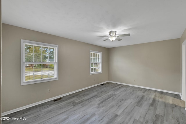 spare room featuring light wood-type flooring, a wealth of natural light, and ceiling fan