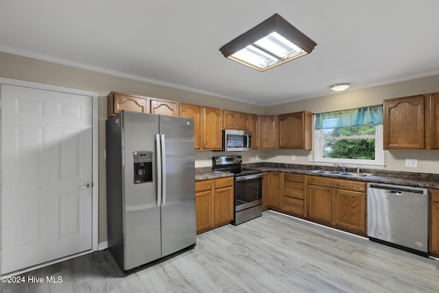 kitchen with light wood-type flooring, stainless steel appliances, crown molding, and sink