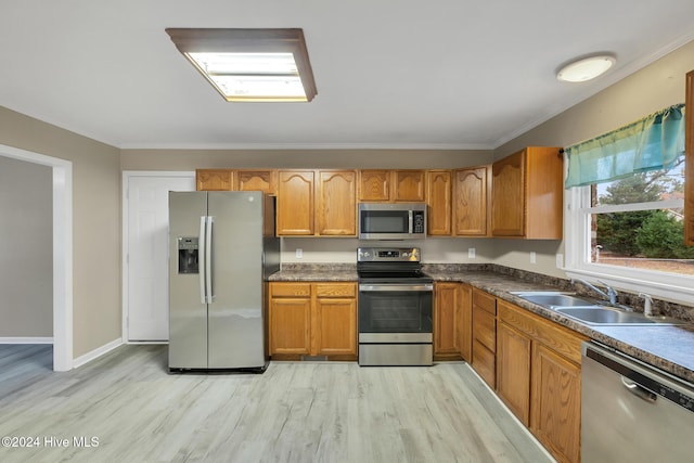 kitchen featuring sink, light wood-type flooring, stainless steel appliances, and ornamental molding