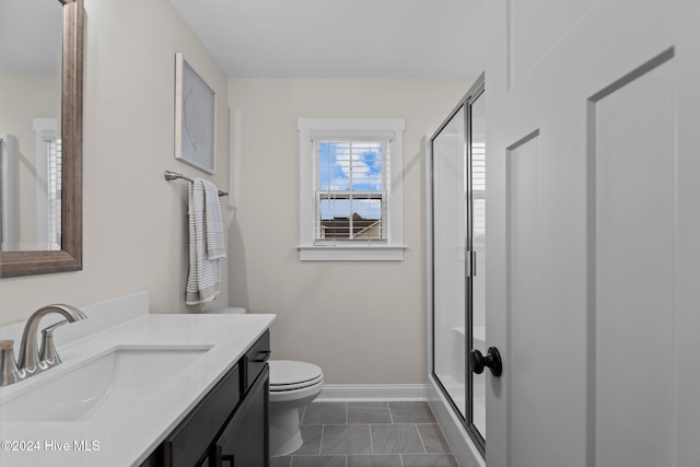 bathroom featuring tile patterned flooring, vanity, toilet, and an enclosed shower