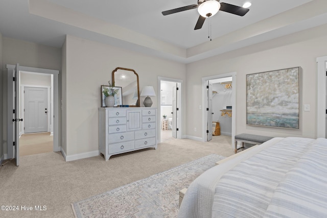 bedroom with a walk in closet, ensuite bath, ceiling fan, light colored carpet, and a closet