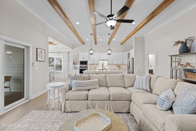 living room with ceiling fan, beamed ceiling, ornamental molding, and light wood-type flooring