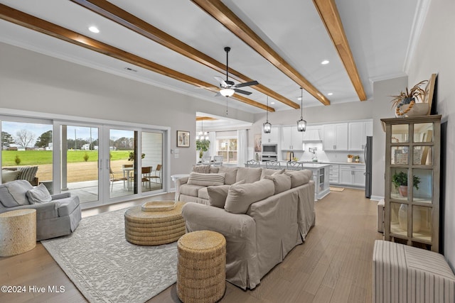 living room featuring beamed ceiling, ceiling fan, light wood-type flooring, and crown molding