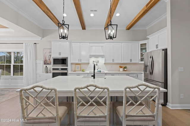 kitchen with pendant lighting, beamed ceiling, stainless steel appliances, and light wood-type flooring