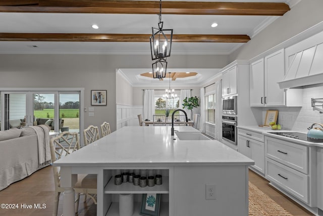 kitchen featuring plenty of natural light, light stone counters, a kitchen island with sink, and decorative light fixtures