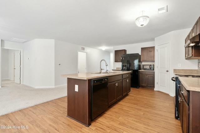 kitchen with black appliances, light hardwood / wood-style floors, a center island with sink, and sink