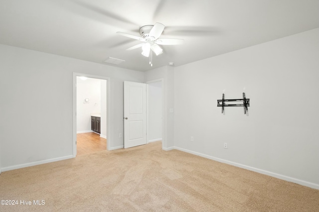 interior space with light colored carpet, ceiling fan, and ensuite bathroom