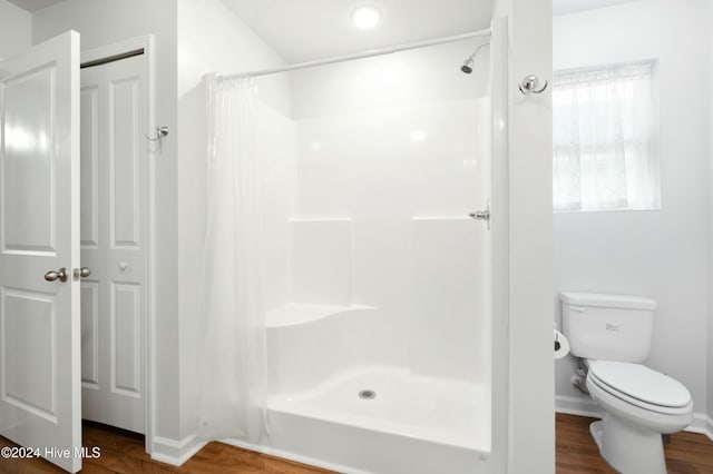 bathroom featuring hardwood / wood-style flooring, toilet, and a shower with shower curtain