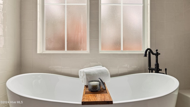 bathroom featuring a bath and tile walls