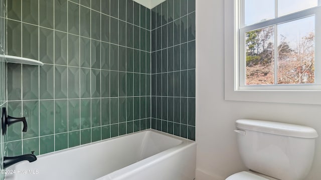 bathroom with toilet and tiled shower / bath