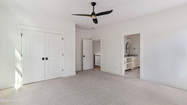 unfurnished bedroom with ceiling fan, sink, ensuite bathroom, light carpet, and a closet