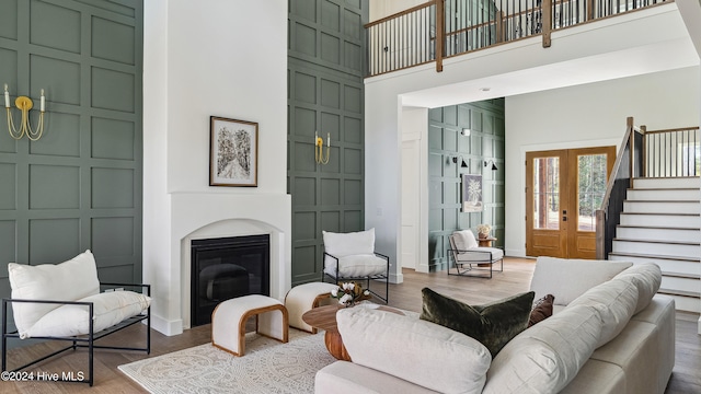 living room with french doors, a towering ceiling, and hardwood / wood-style flooring