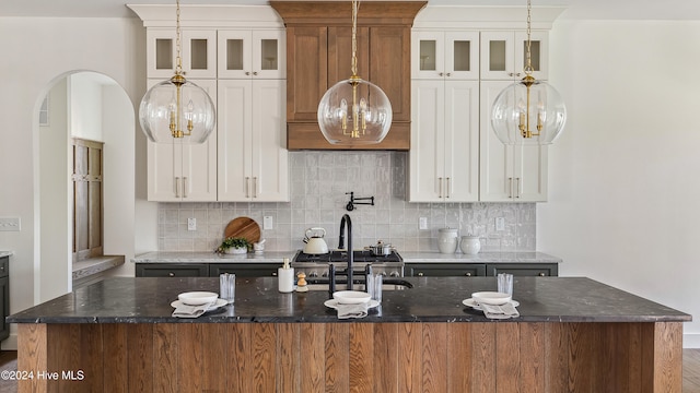 kitchen with white cabinetry, an island with sink, and dark stone counters