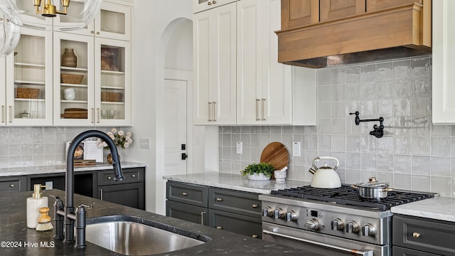 kitchen with premium range hood, decorative backsplash, white cabinetry, and high end stainless steel range oven