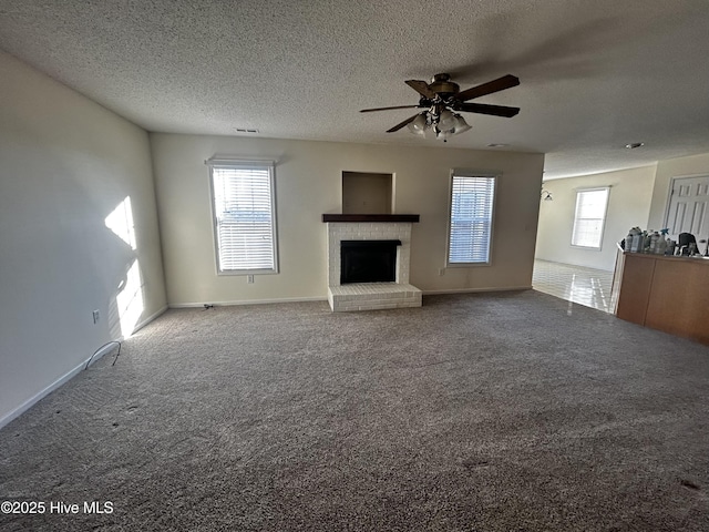 unfurnished living room with carpet, a textured ceiling, ceiling fan, and a fireplace