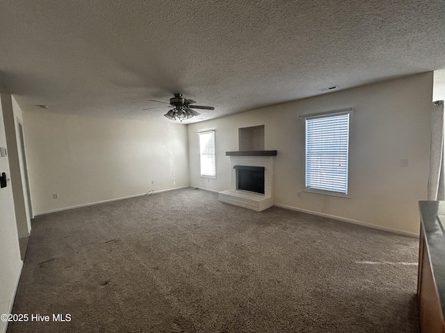 unfurnished living room with a fireplace, a textured ceiling, dark carpet, and ceiling fan