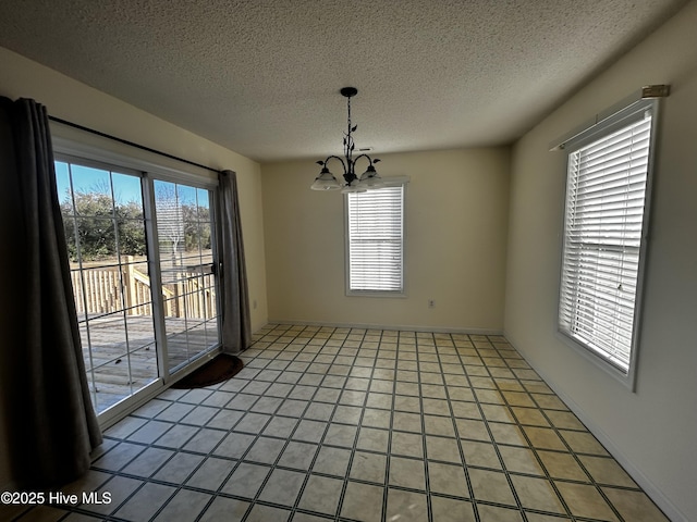 unfurnished dining area with tile patterned flooring, a healthy amount of sunlight, a textured ceiling, and an inviting chandelier