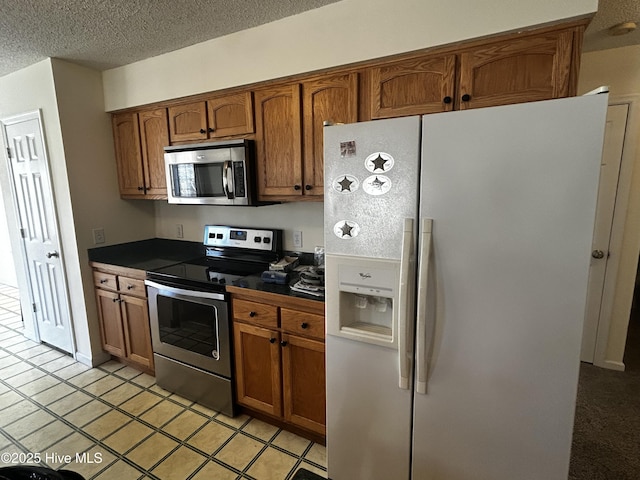 kitchen with appliances with stainless steel finishes, a textured ceiling, and light tile patterned floors