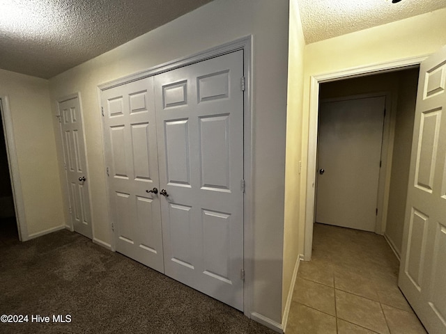 hall featuring tile patterned floors and a textured ceiling