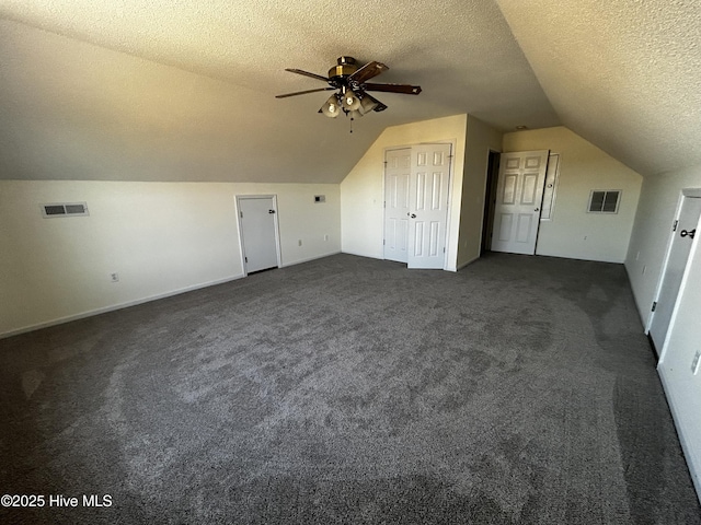 bonus room with a textured ceiling, dark carpet, ceiling fan, and vaulted ceiling