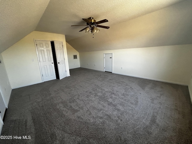 bonus room featuring dark colored carpet, ceiling fan, a textured ceiling, and vaulted ceiling