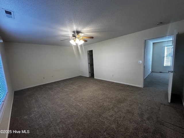 empty room featuring a textured ceiling, dark carpet, and ceiling fan