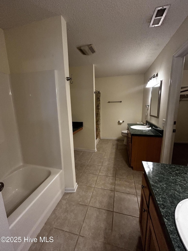 full bathroom featuring vanity, plus walk in shower, tile patterned flooring, toilet, and a textured ceiling