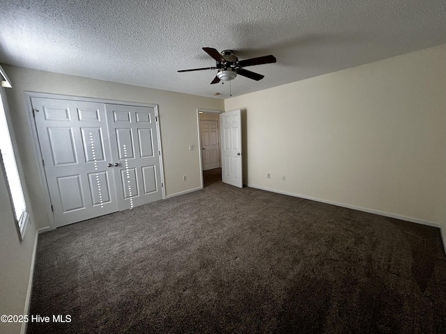 unfurnished bedroom with ceiling fan, dark carpet, and a textured ceiling