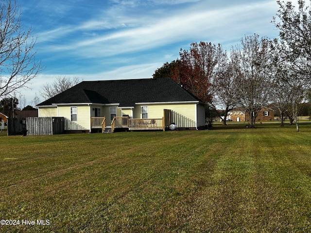 rear view of house featuring a lawn and a wooden deck