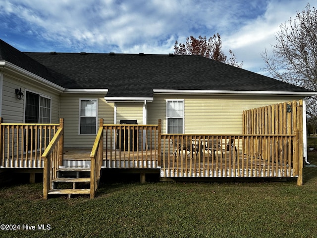 rear view of house featuring a deck and a lawn