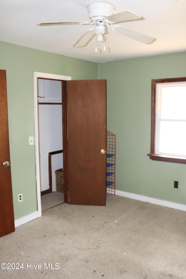 unfurnished bedroom featuring ceiling fan, a closet, and light colored carpet