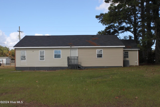 rear view of property featuring central AC unit and a yard