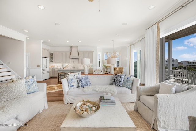 living room with ceiling fan with notable chandelier, light hardwood / wood-style floors, and crown molding