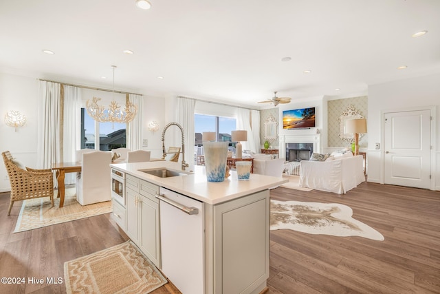 kitchen featuring light wood-type flooring, custom range hood, stainless steel appliances, sink, and decorative light fixtures