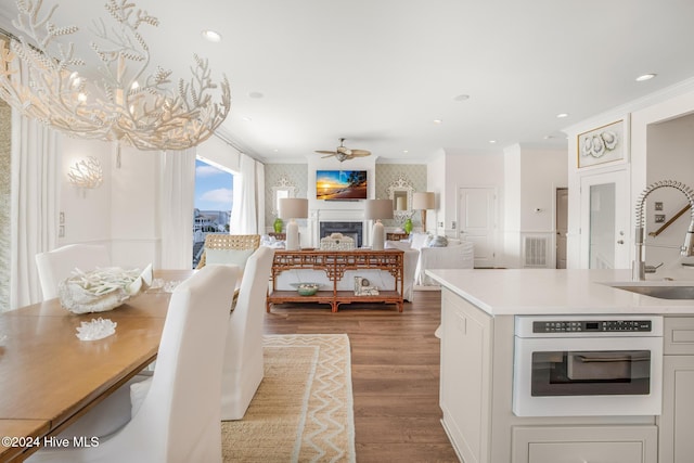 dining space featuring hardwood / wood-style flooring, ceiling fan with notable chandelier, and ornamental molding