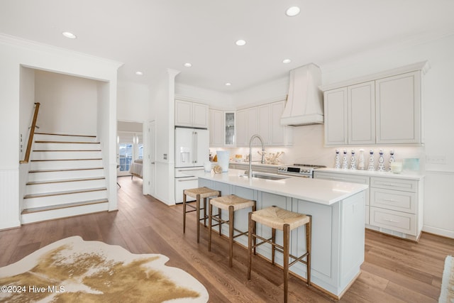 kitchen featuring white cabinets, oven, crown molding, sink, and hardwood / wood-style flooring