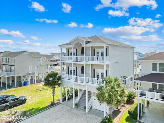 beach home with french doors, a balcony, a water view, a carport, and a garage