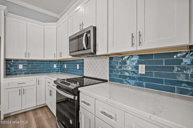 kitchen with backsplash, light wood-type flooring, ornamental molding, white cabinetry, and stainless steel appliances