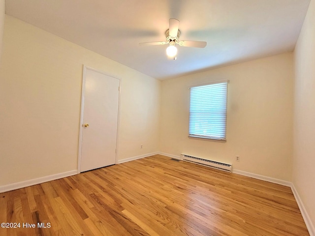 empty room with ceiling fan, light hardwood / wood-style floors, and a baseboard heating unit