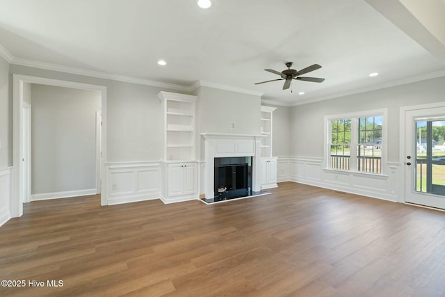 unfurnished living room featuring a fireplace with raised hearth, a decorative wall, a ceiling fan, recessed lighting, and wood finished floors