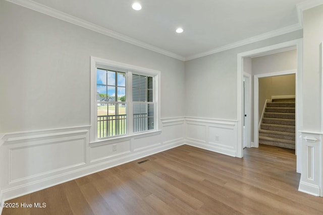 spare room featuring recessed lighting, crown molding, a wainscoted wall, visible vents, and wood finished floors