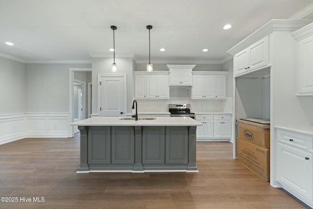 kitchen featuring stainless steel electric stove, white cabinetry, wood finished floors, light countertops, and a sink