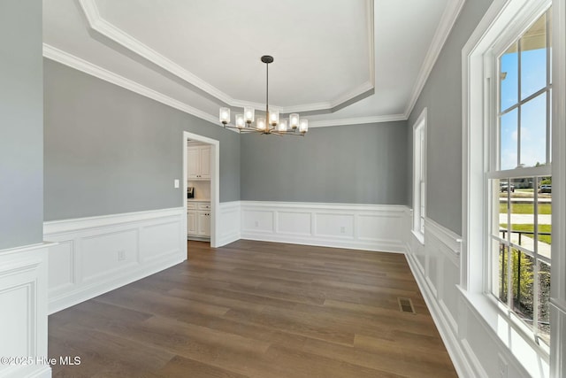 unfurnished dining area featuring a notable chandelier, dark wood-style floors, crown molding, visible vents, and a raised ceiling