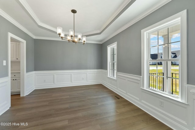 unfurnished dining area with a raised ceiling, dark wood-type flooring, a notable chandelier, and visible vents