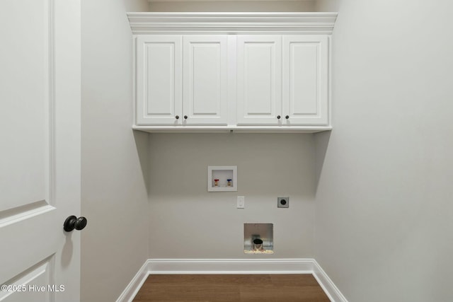 clothes washing area featuring electric dryer hookup, baseboards, washer hookup, cabinet space, and wood finished floors