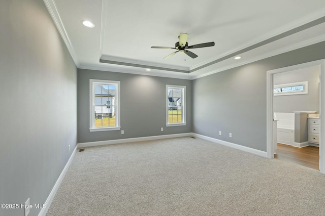 unfurnished bedroom with baseboards, carpet flooring, a tray ceiling, and crown molding