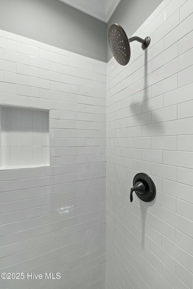 interior details featuring a tile shower and ornamental molding